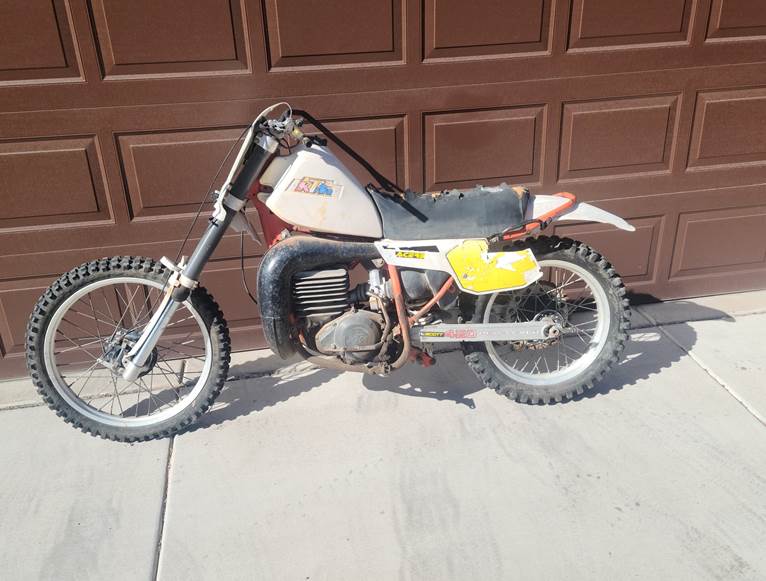 A dirt bike parked in front of a garage door

Description automatically generated